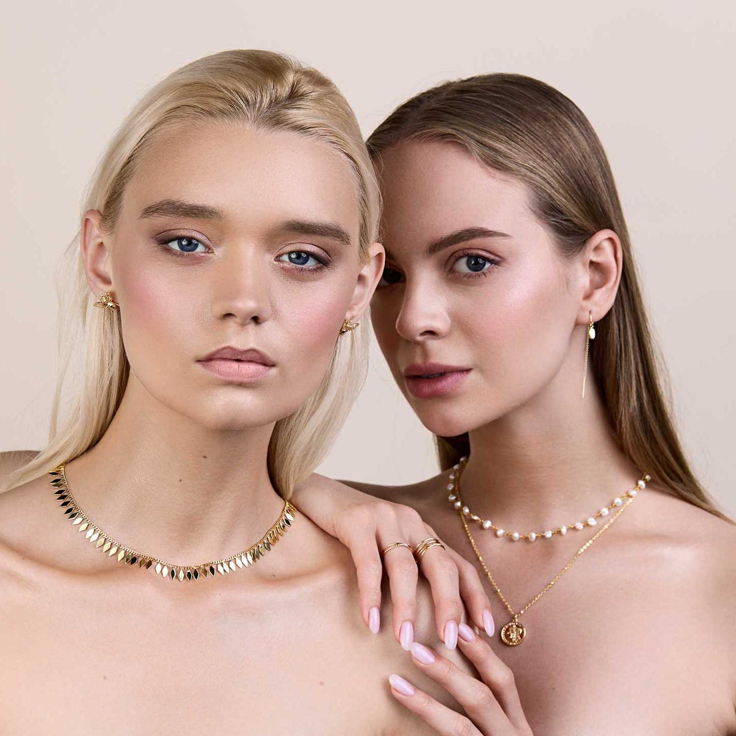 Two girls looking at the camera wearing earrings and necklaces
