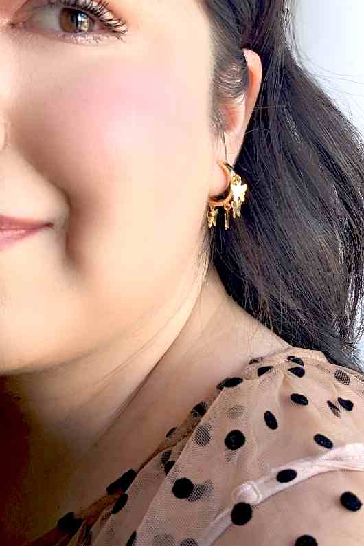 Load image into Gallery viewer, A model wearing gold butterfly hoop earrings
