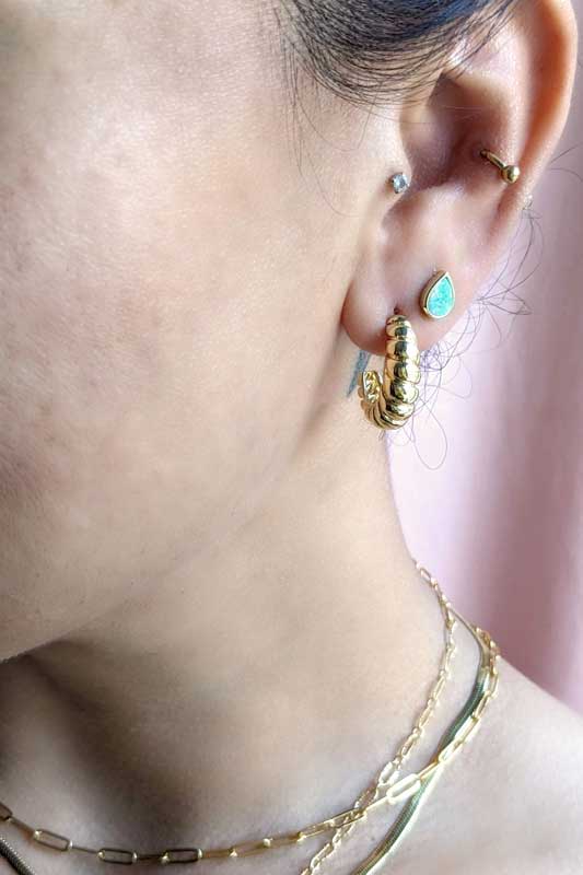 
                  
                    Croissant shaped gold hoops on a model
                  
                