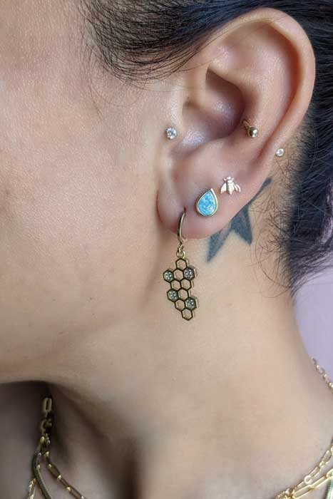 model wearing honeycomb dangles and opal stud earrings