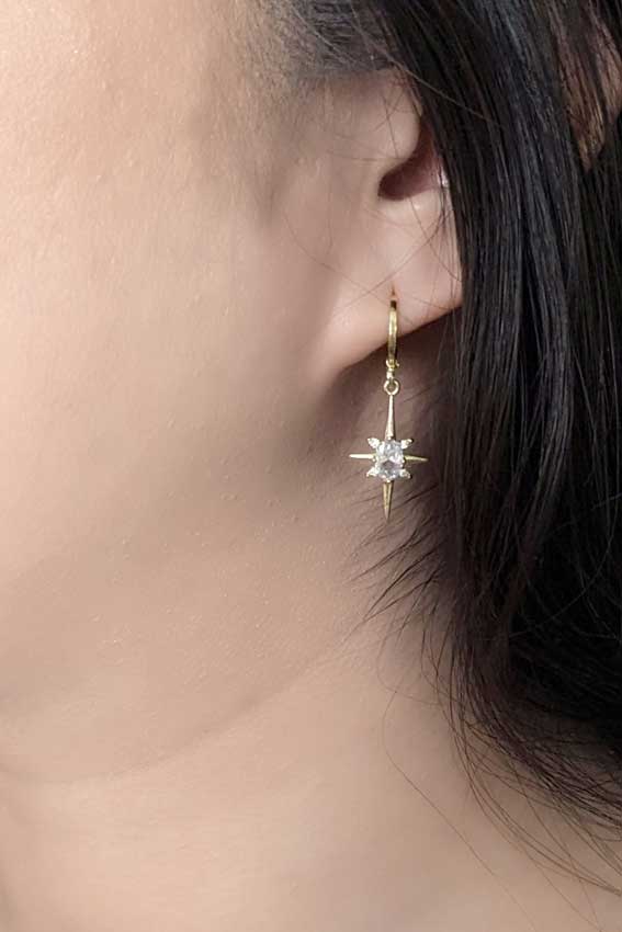 Gold North Star Earrings on a model
