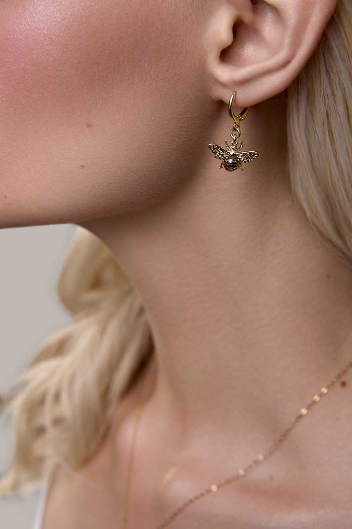Girl wearing gold bee dangle earrings