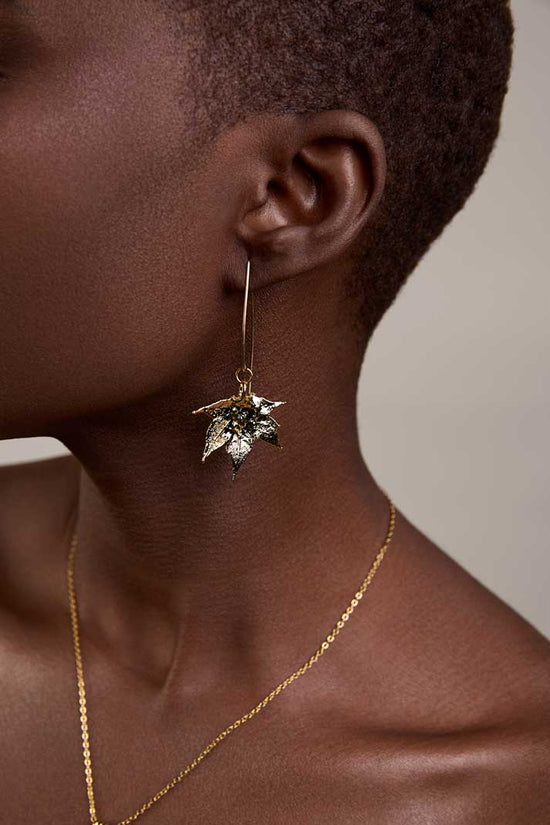 Girl wearing maple leaf gold earrings that are made of natural leaves