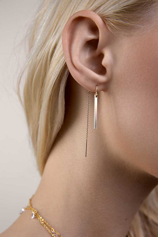 Girl with hair aside wearing gold bar threader earrings