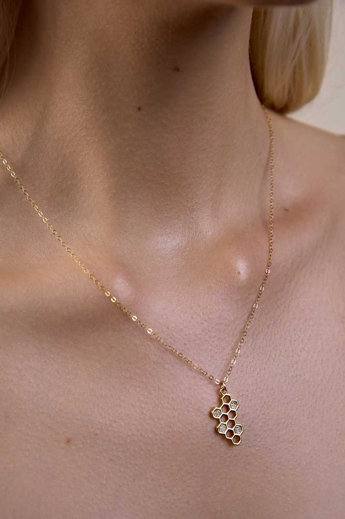 Neck showing a gold honeycomb necklace