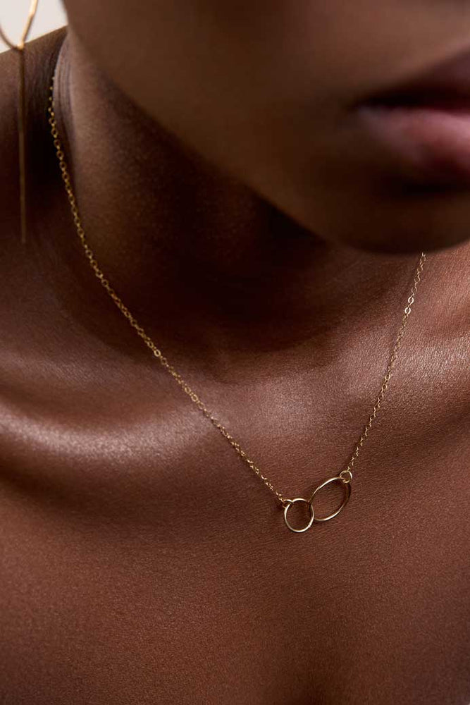 
                  
                    Neck showing dainty interlocked circles gold necklace
                  
                
