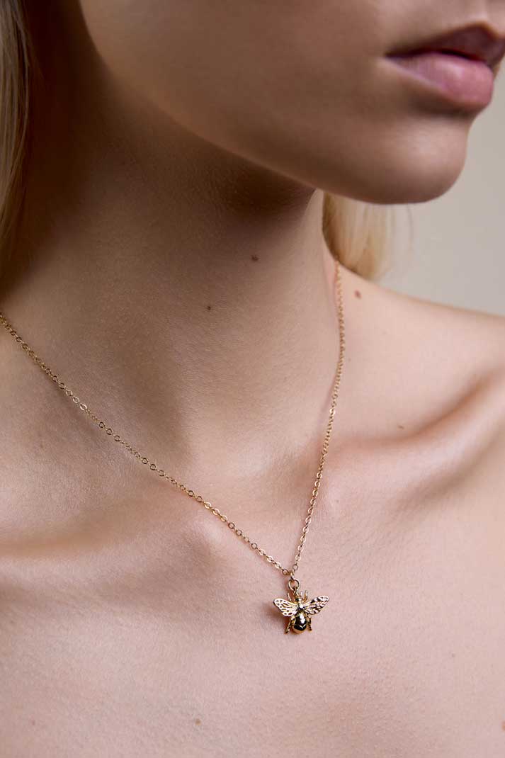 Neck showing gold honey bee necklace.